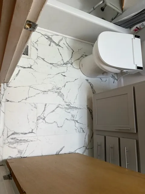 Bathroom with marble-look wall tile and a new floor beside the vanity