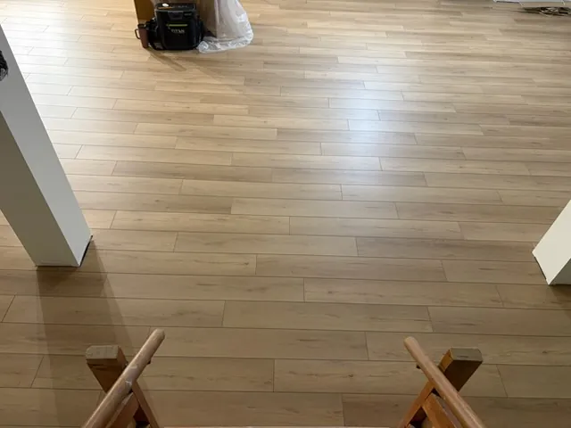 New light plank floor running through an open room, seen from a doorway